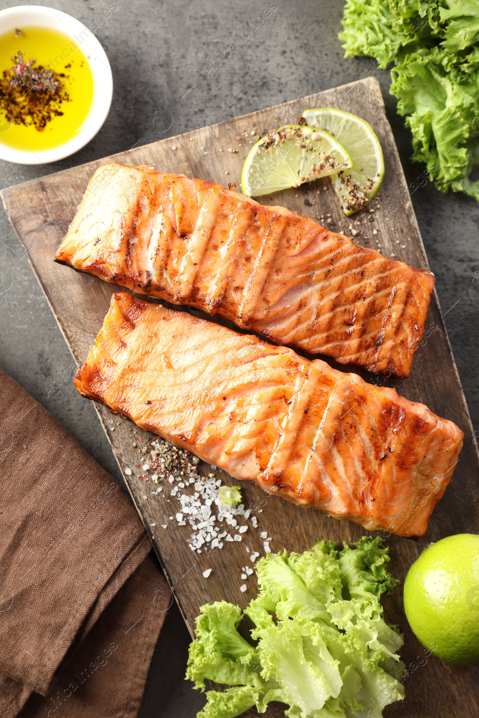 Photo of Delicious grilled salmon fillets served on grey textured table, flat lay