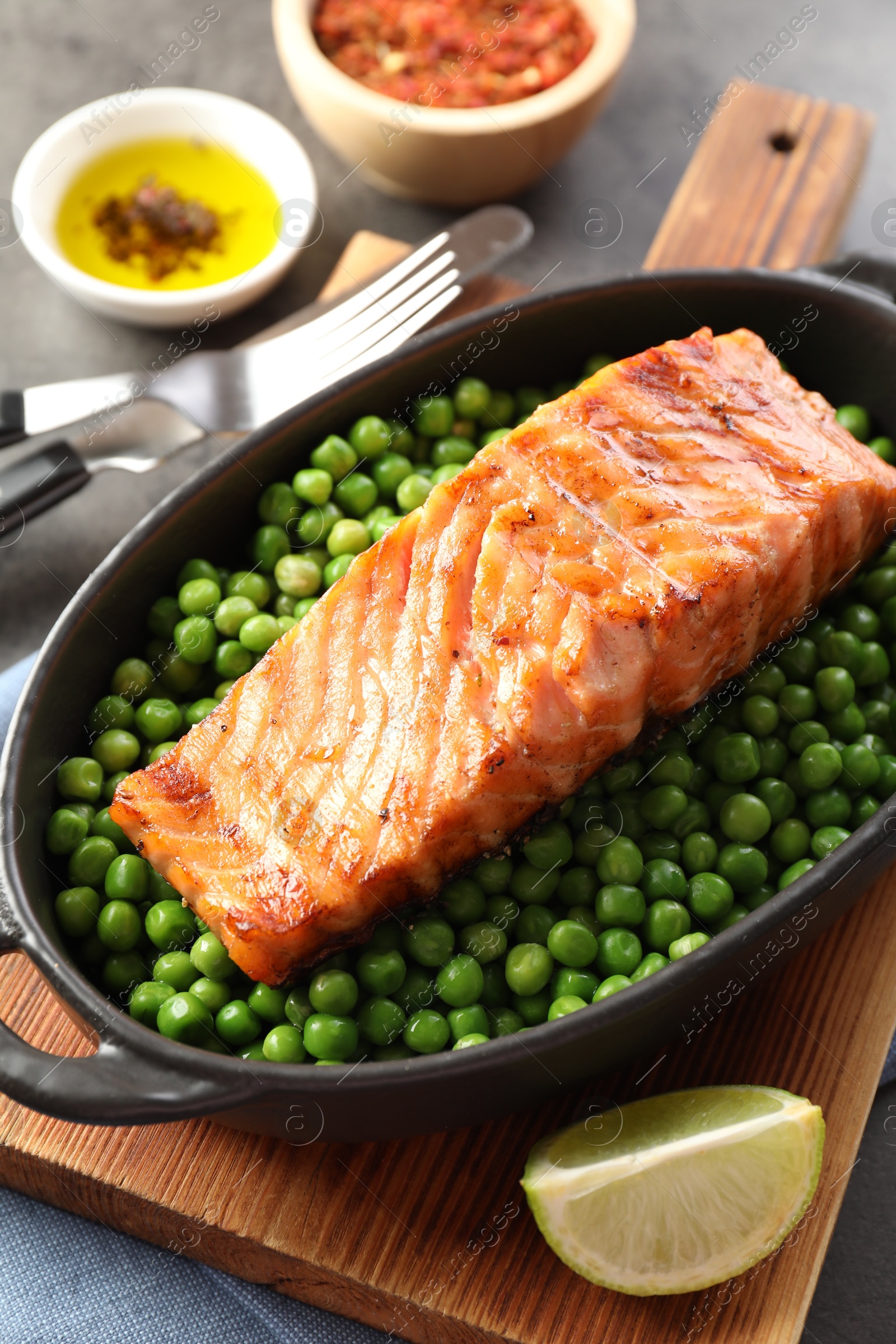 Photo of Delicious grilled salmon fillet in baking dish served on grey table, closeup