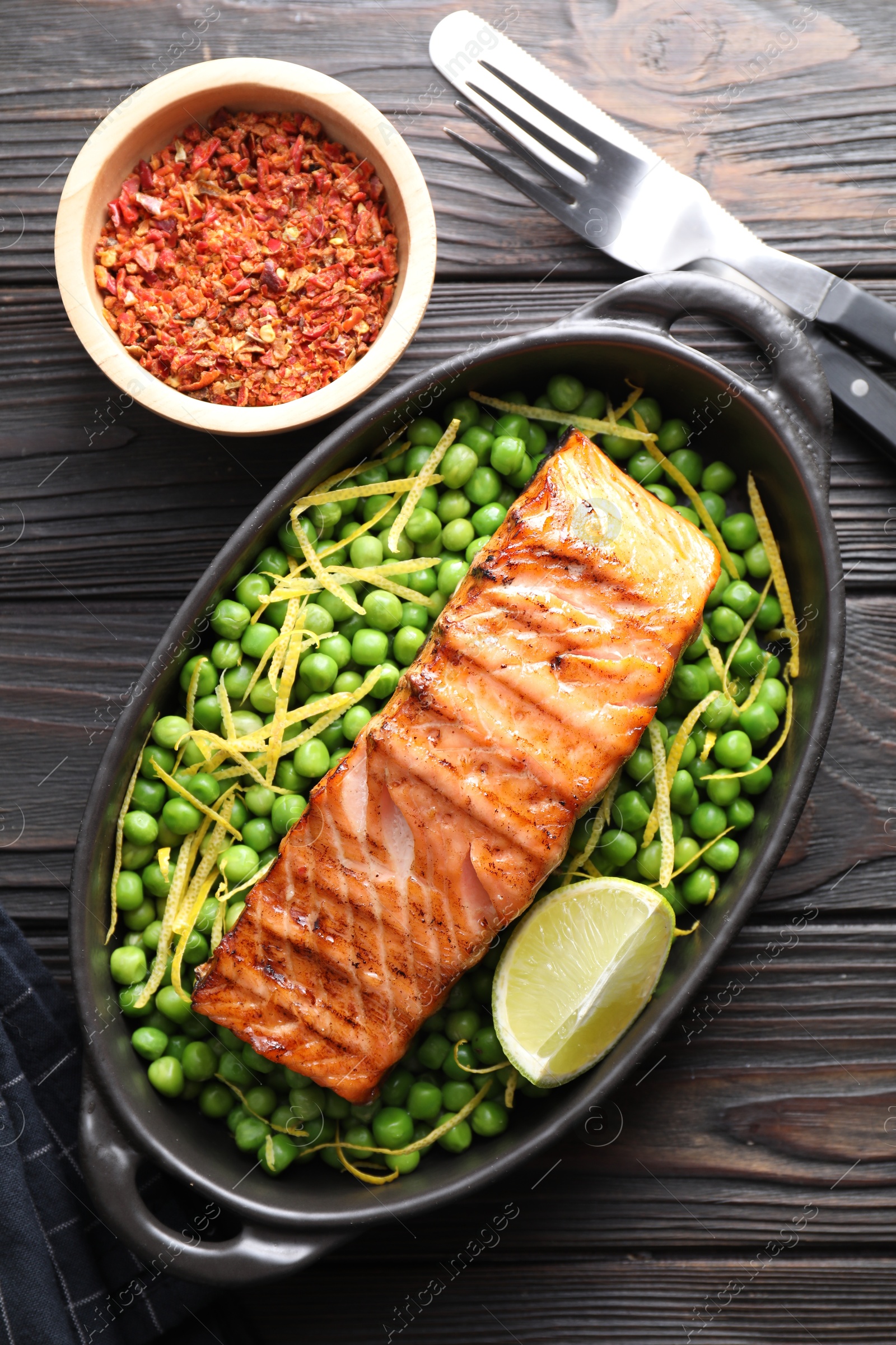 Photo of Delicious grilled salmon fillet in baking dish served on wooden table, flat lay