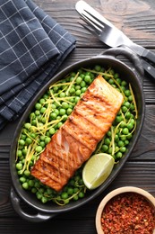 Photo of Delicious grilled salmon fillet in baking dish served on wooden table, flat lay