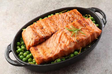 Photo of Delicious grilled salmon fillets with rosemary and green peas in baking dish on grey textured table, closeup