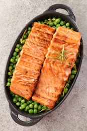 Photo of Delicious grilled salmon fillets with rosemary and green peas in baking dish on grey textured table, top view