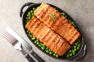 Photo of Delicious grilled salmon fillets in baking dish served on grey textured table, flat lay