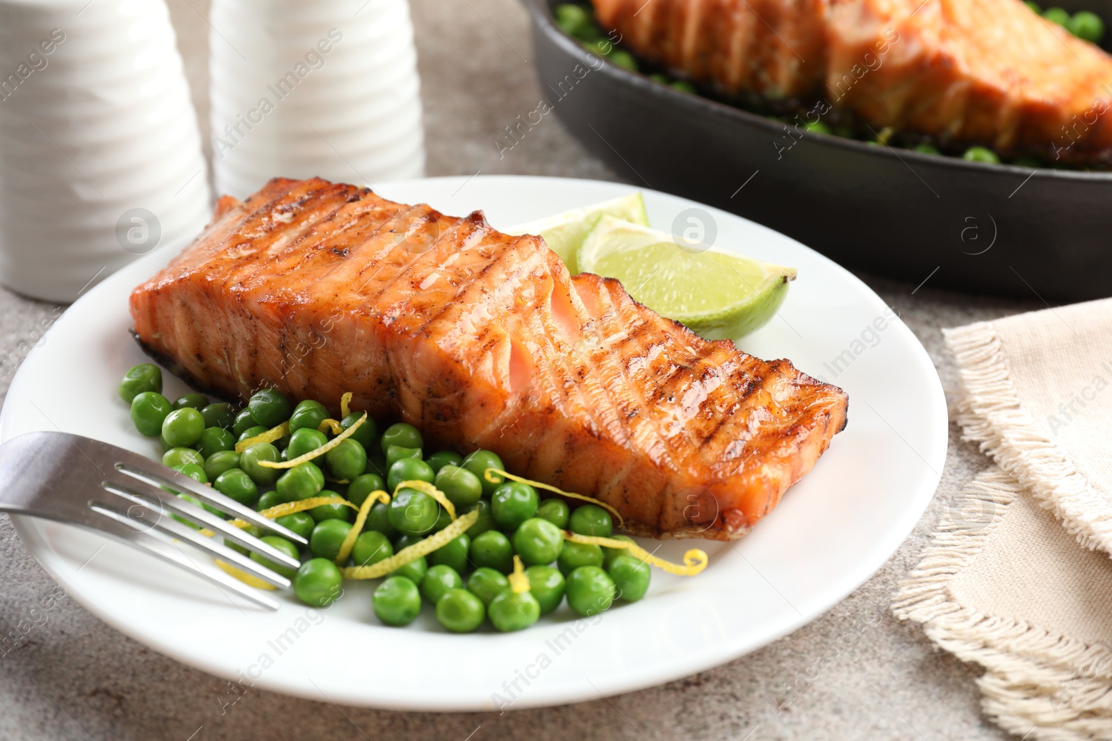 Photo of Delicious grilled salmon fillet served on grey textured table, closeup