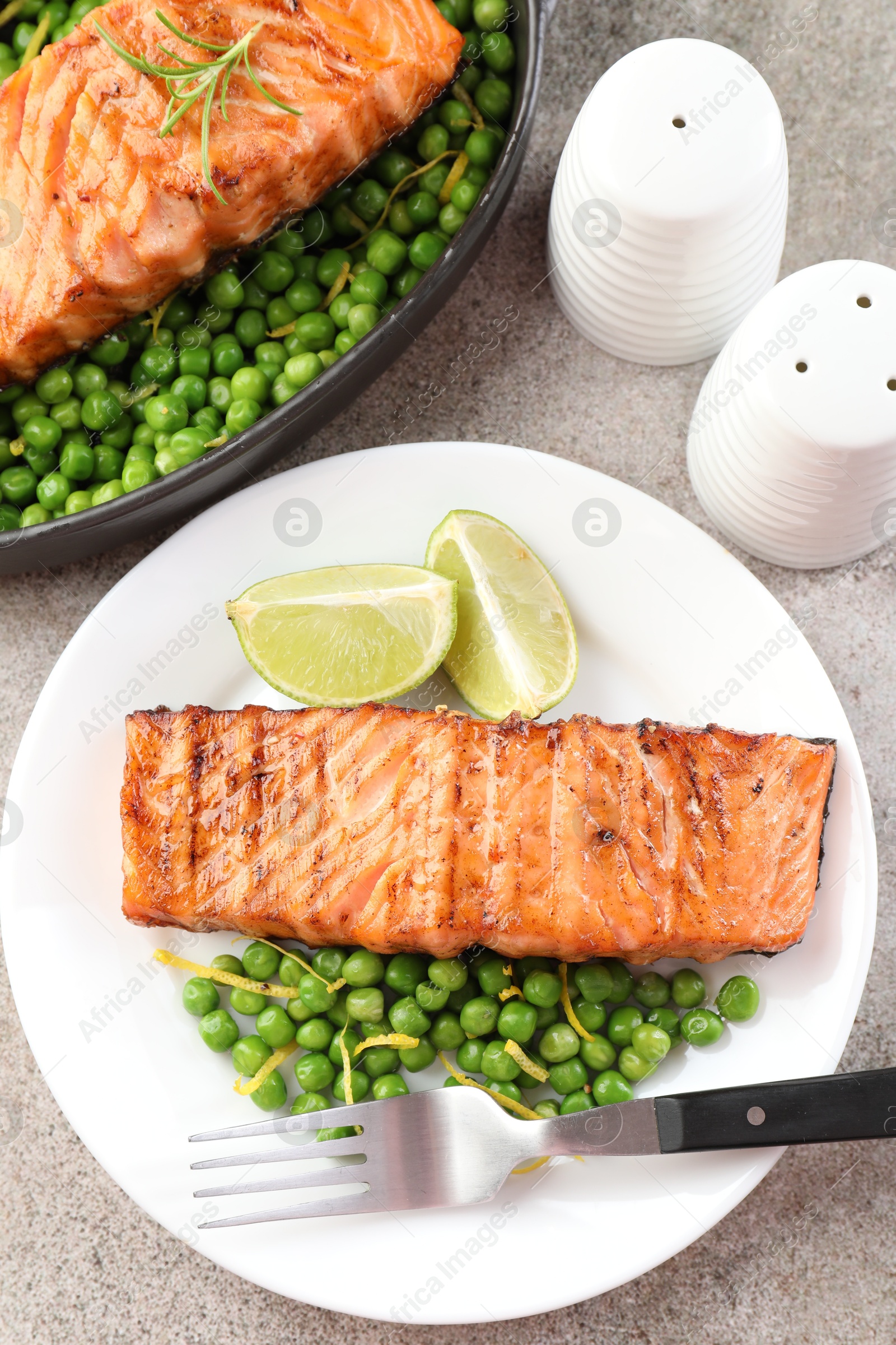 Photo of Delicious grilled salmon fillets served on grey textured table, flat lay