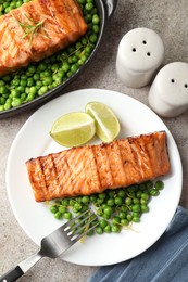 Delicious grilled salmon fillet served on grey textured table, flat lay