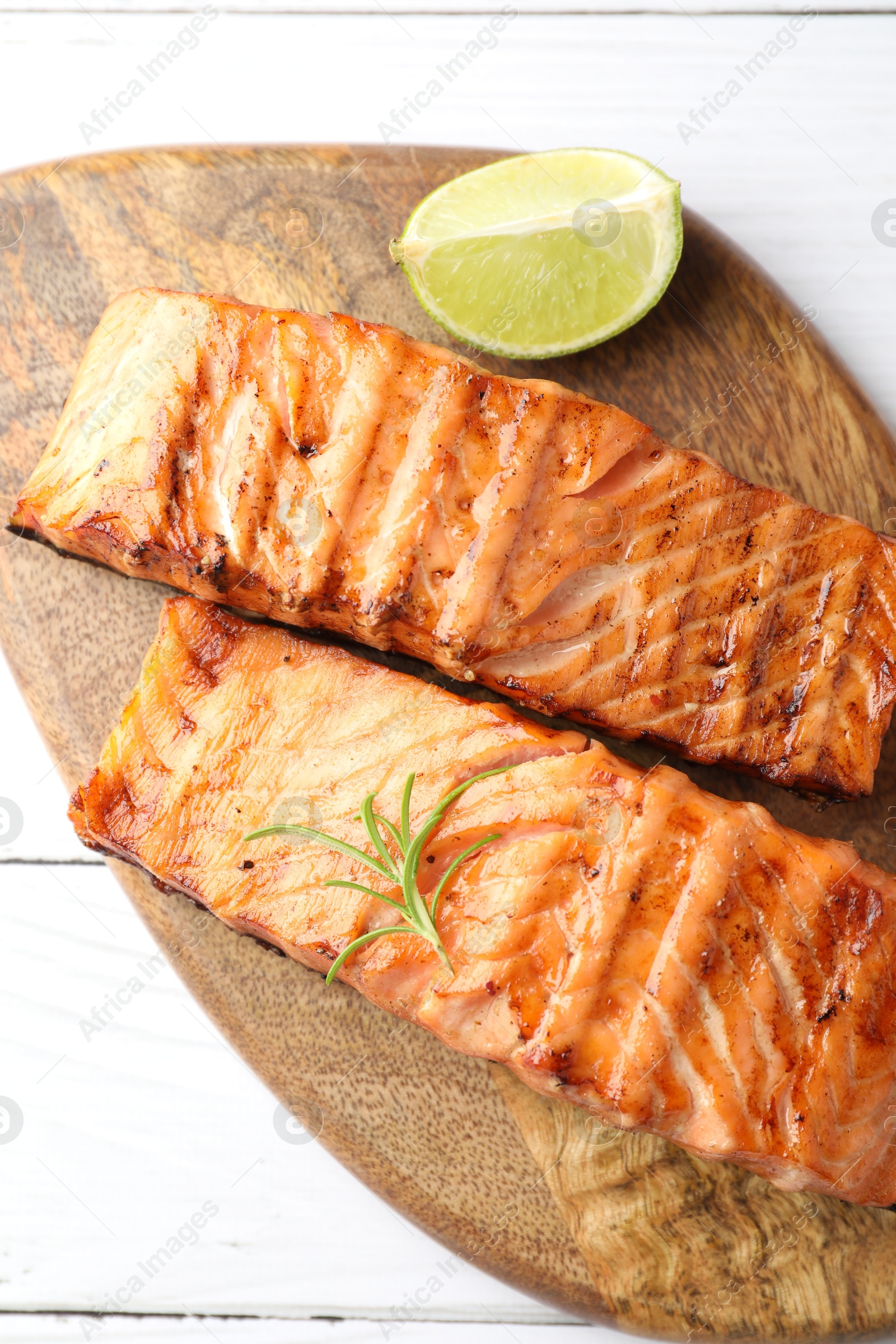 Photo of Delicious grilled salmon fillets with lime and rosemary on white wooden table, top view