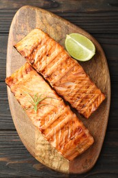 Delicious grilled salmon fillets with lime and rosemary on wooden table, top view