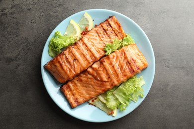 Photo of Delicious grilled salmon fillets with lettuce and lemon on grey table, top view