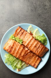 Delicious grilled salmon fillets with lettuce and lemon on grey table, top view