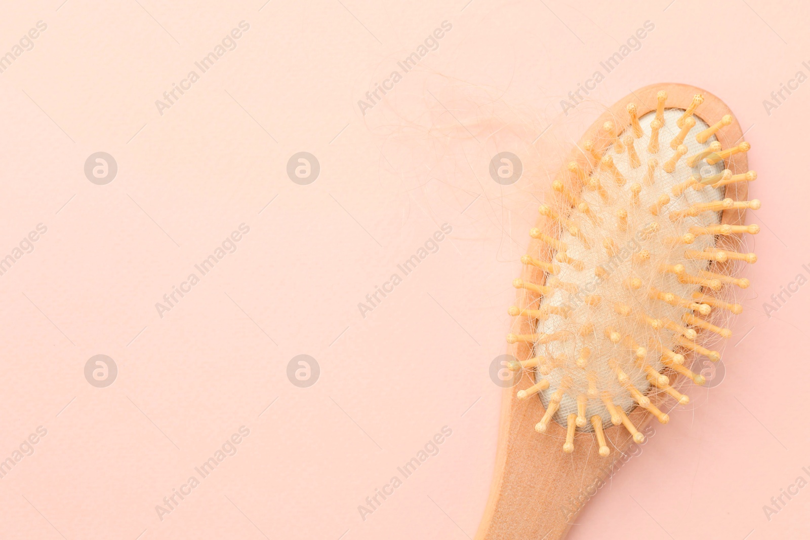 Photo of One brush with lost hair on light pink background, top view. Space for text