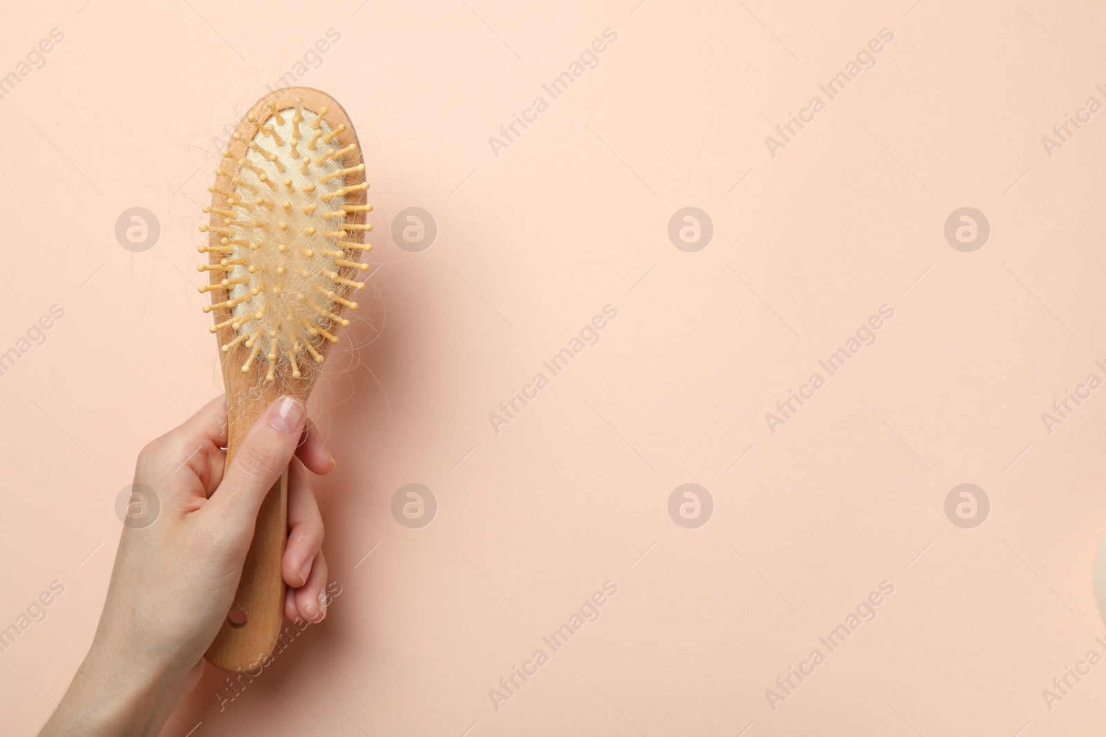 Photo of Woman with brush and lost hair on light pink background, top view. Space for text