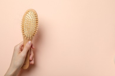 Photo of Woman with brush and lost hair on light pink background, top view. Space for text