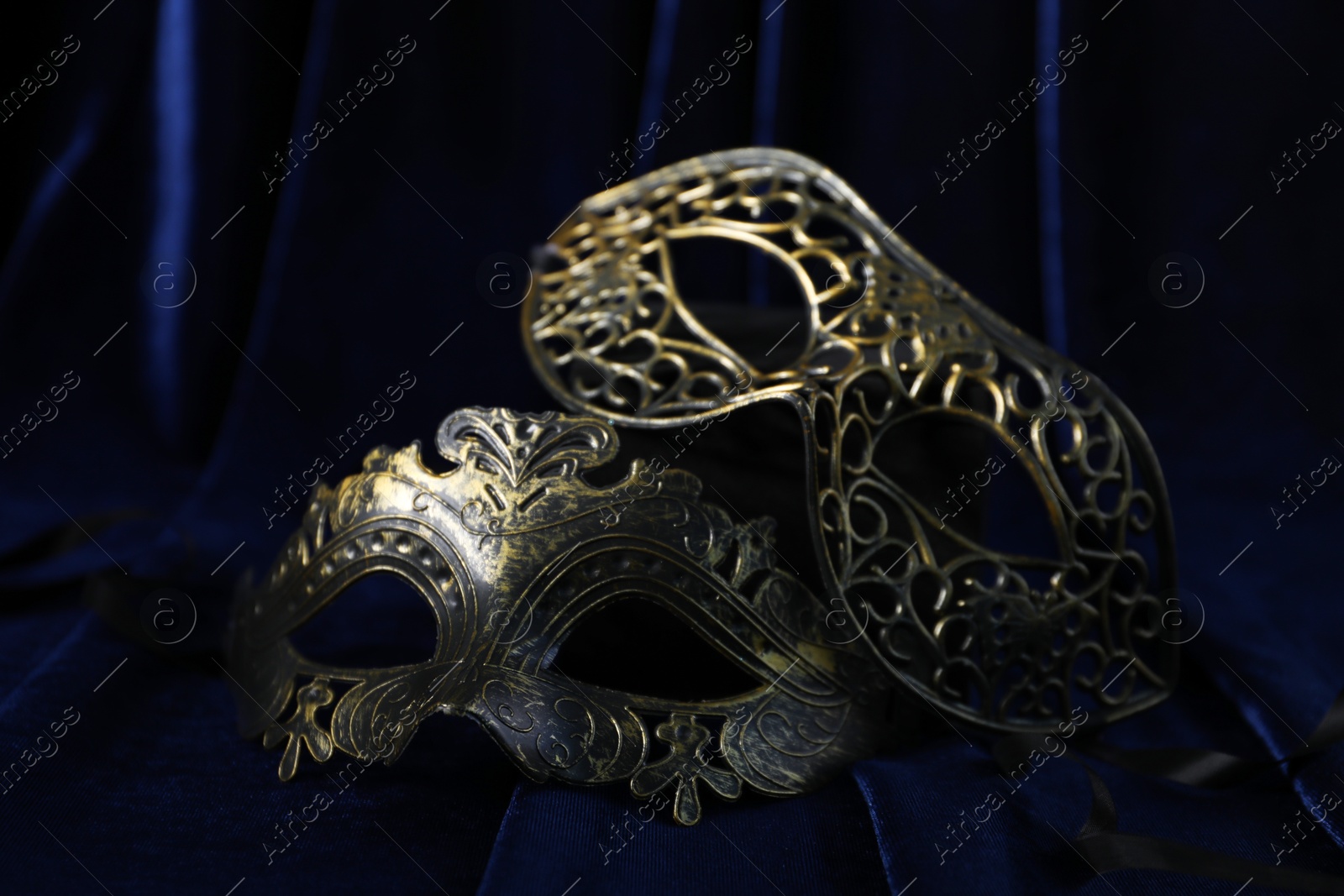 Photo of Beautiful carnival masks on blue fabric, closeup