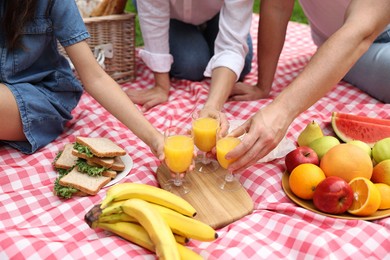 Photo of Family having picnic on checkered blanket outdoors, closeup