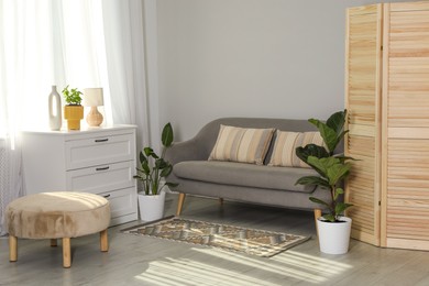 Photo of Wooden folding screen, sofa and houseplants in living room