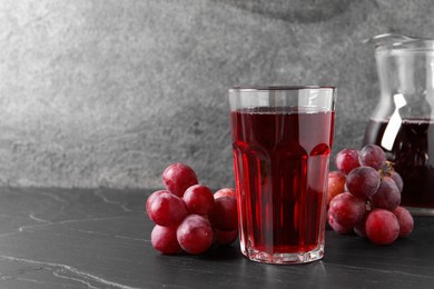 Photo of Tasty grape juice and berries on dark textured table. Space for text