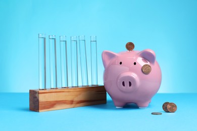 Photo of Water save concept. Piggy bank, coins and liquid in test tubes on light blue background