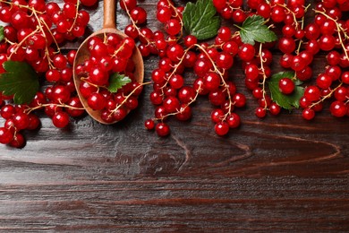 Photo of Fresh red currants and green leaves on wooden table, top view. Space for text