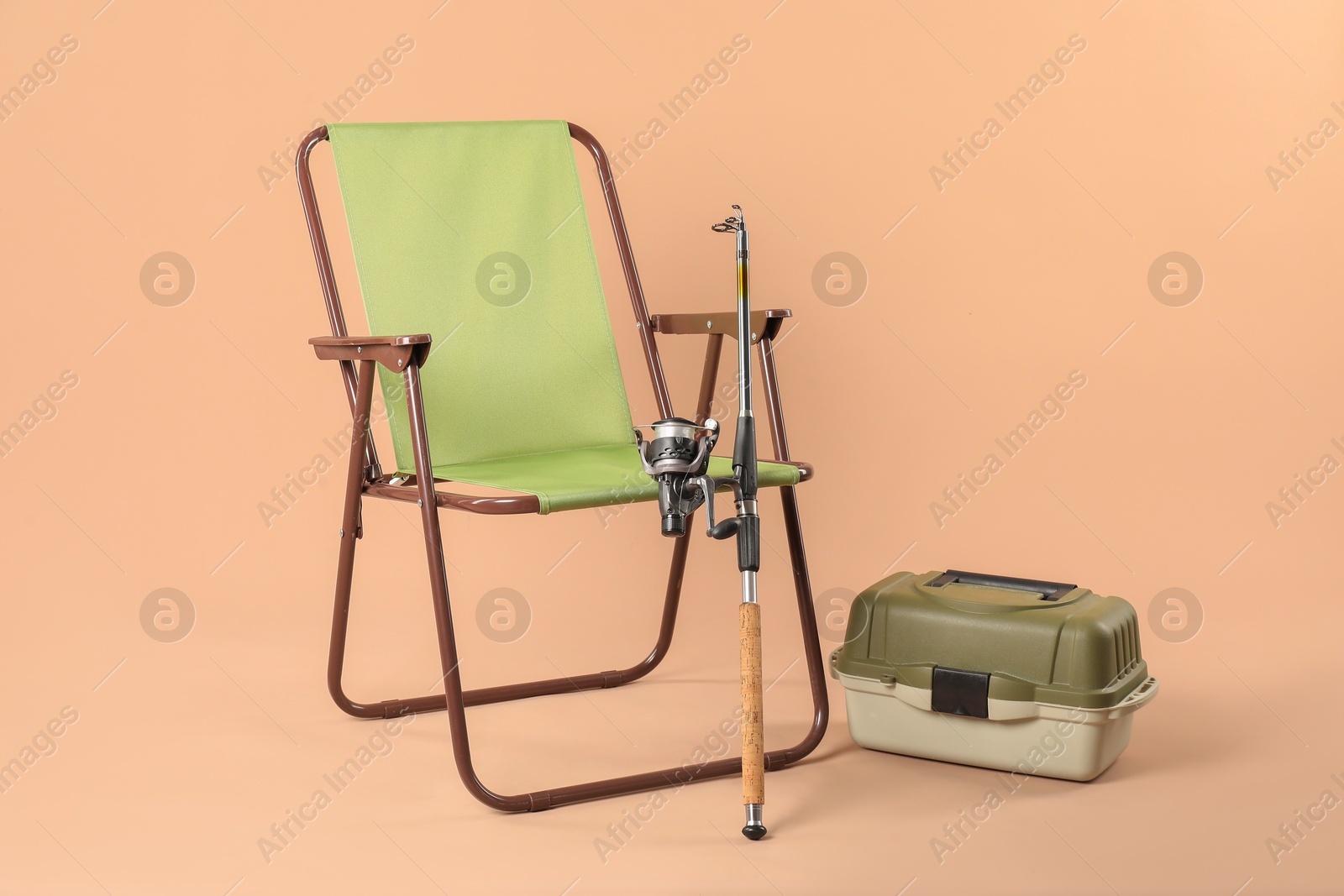 Photo of Folding chair, fishing rod and tackle box on beige background