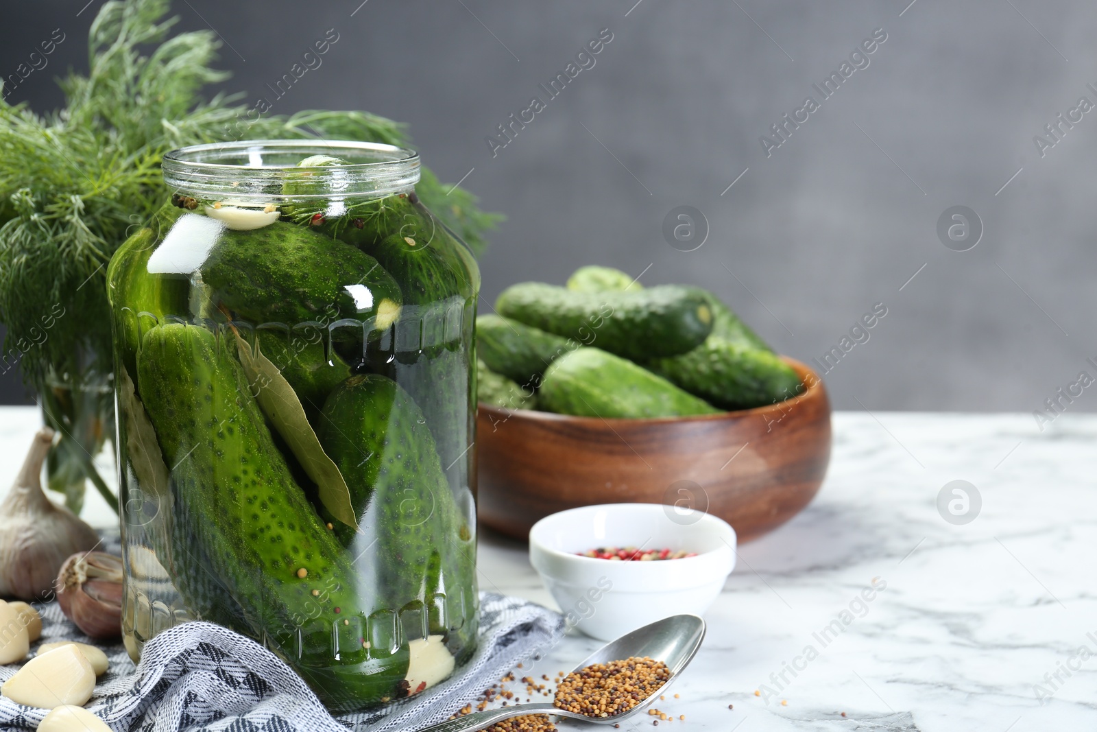 Photo of Making pickles. Fresh cucumbers and spices in jar on white marble table