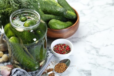 Photo of Making pickles. Fresh cucumbers and spices in jar on white marble table, space for text