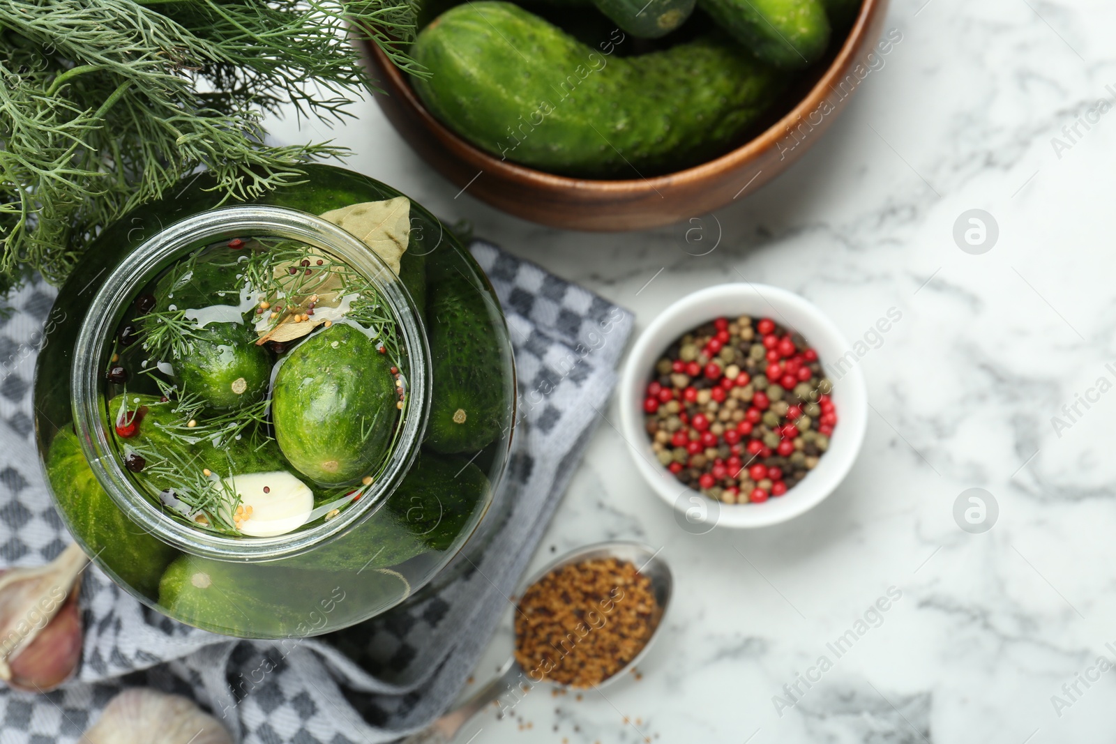 Photo of Making pickles. Fresh cucumbers and spices in jar on white marble table, top view