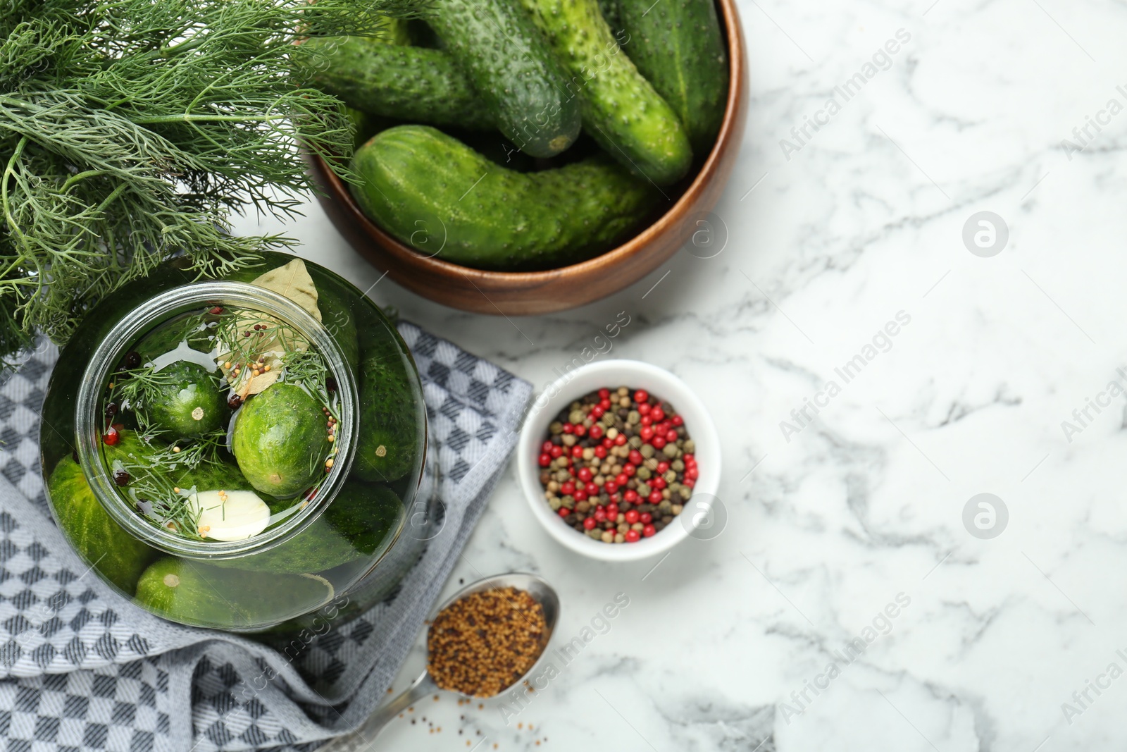 Photo of Making pickles. Fresh cucumbers and spices in jar on white marble table, top view. Space for text