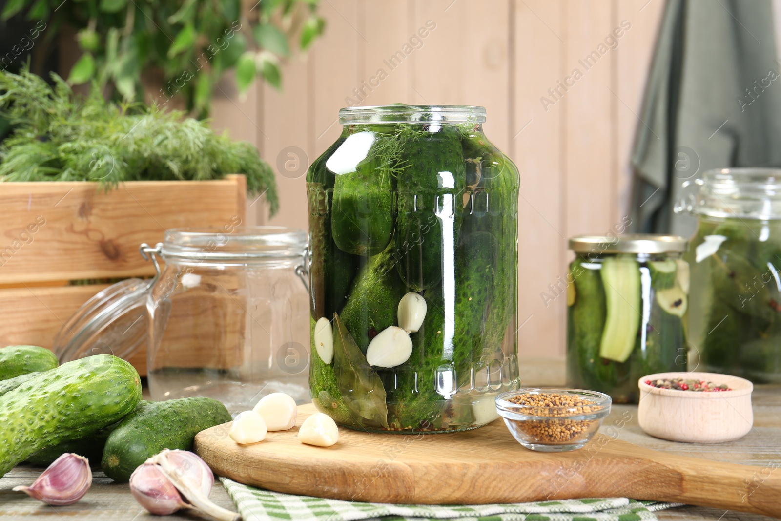 Photo of Making pickles. Fresh cucumbers and spices in jars on wooden table