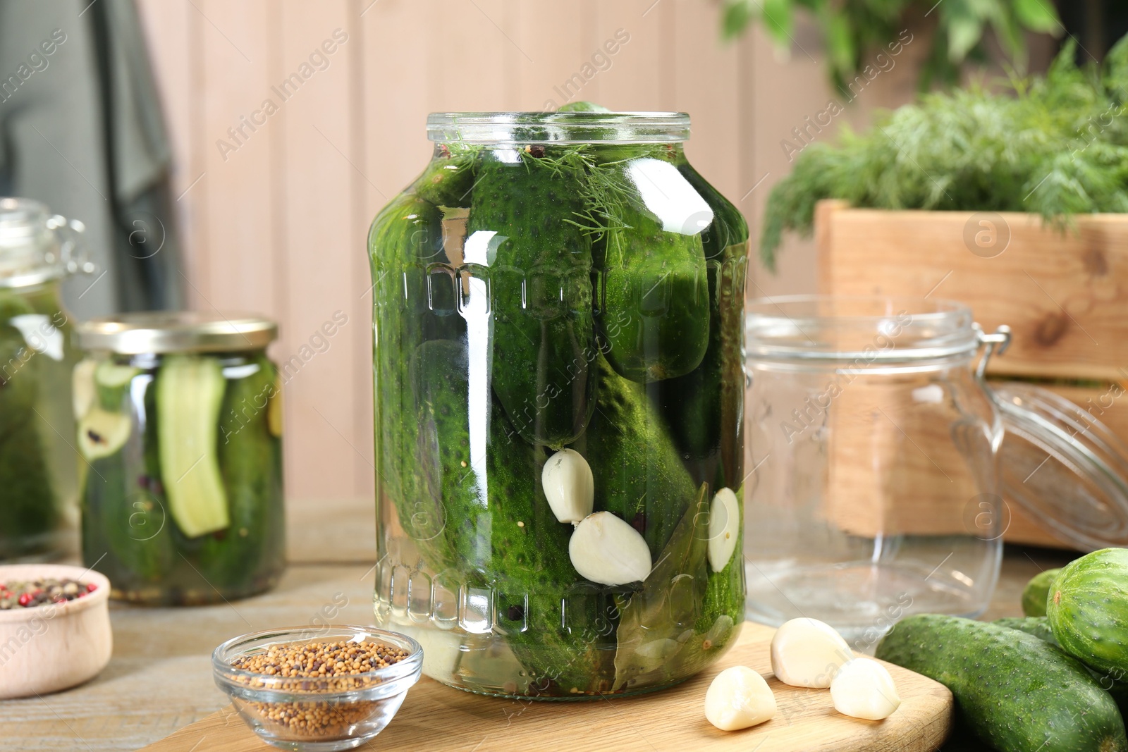 Photo of Making pickles. Fresh cucumbers and spices in jars on wooden table