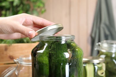 Photo of Woman making pickled cucumbers at table, closeup