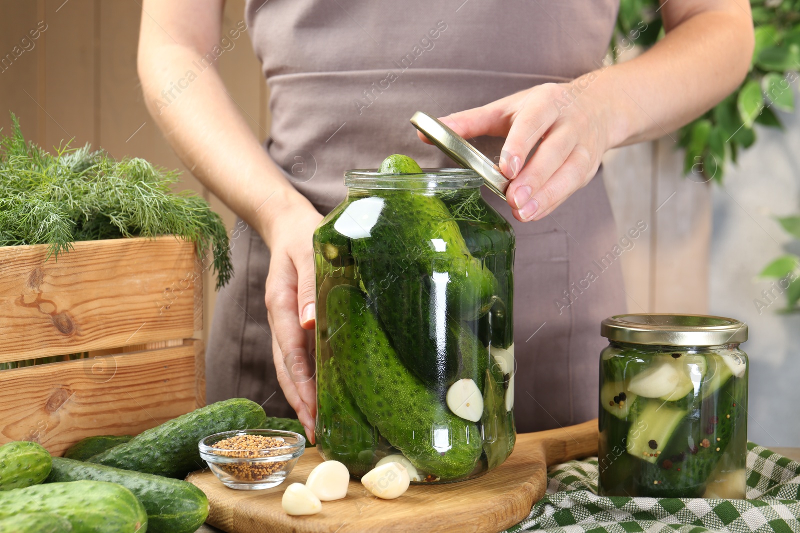 Photo of Woman making pickled cucumbers at table, closeup