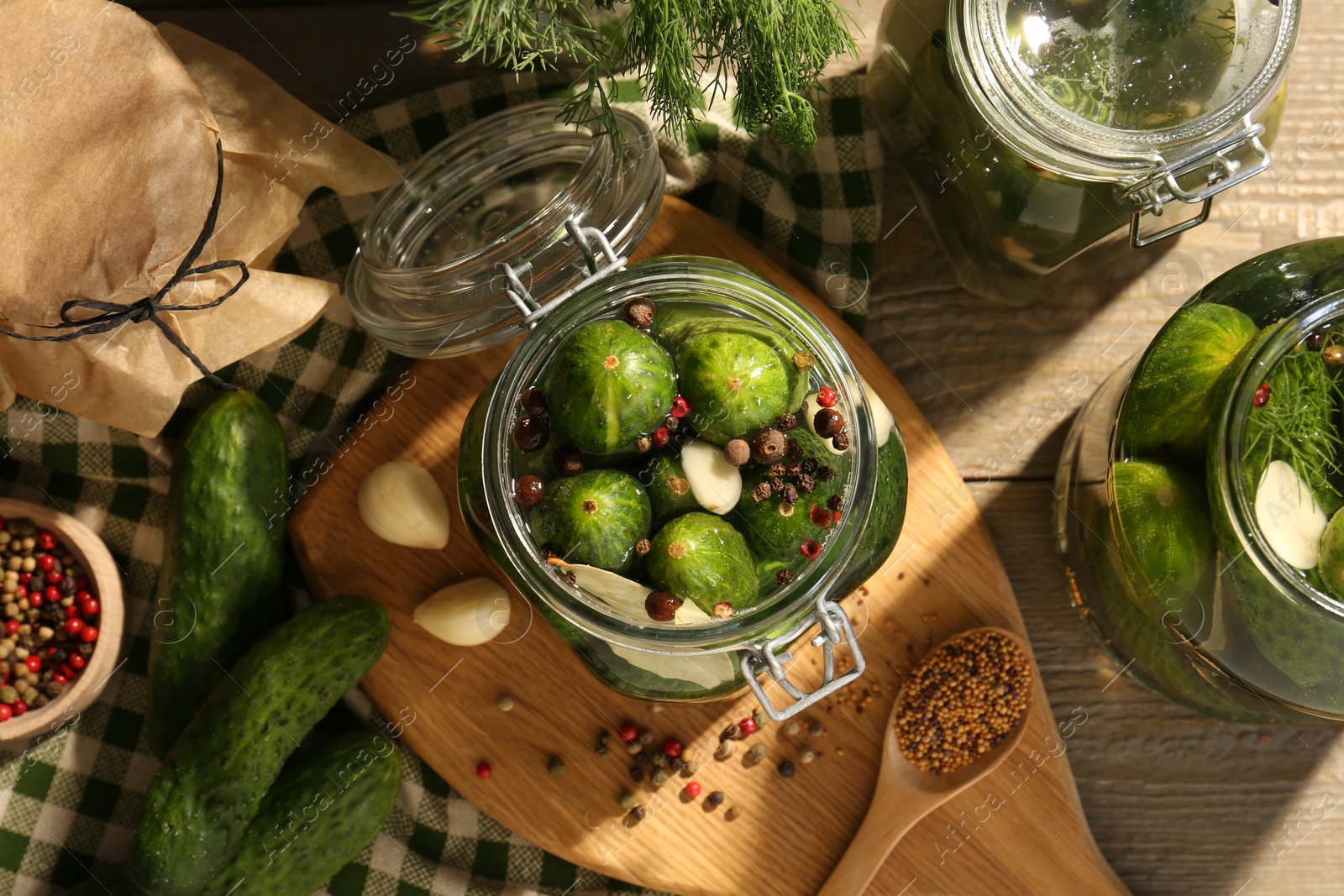 Photo of Making pickles. Fresh cucumbers and spices in jars on wooden table, top view