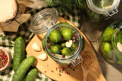 Photo of Making pickles. Fresh cucumbers and spices in jars on wooden table, top view