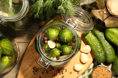 Photo of Making pickles. Fresh cucumbers and spices in jars on wooden table, top view