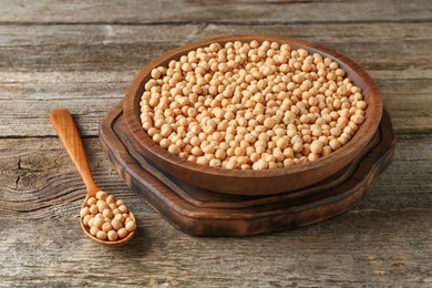 Photo of Dried peas in bowl and spoon on wooden table, closeup