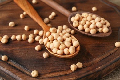 Photo of Spoons with dried peas on wooden table, closeup