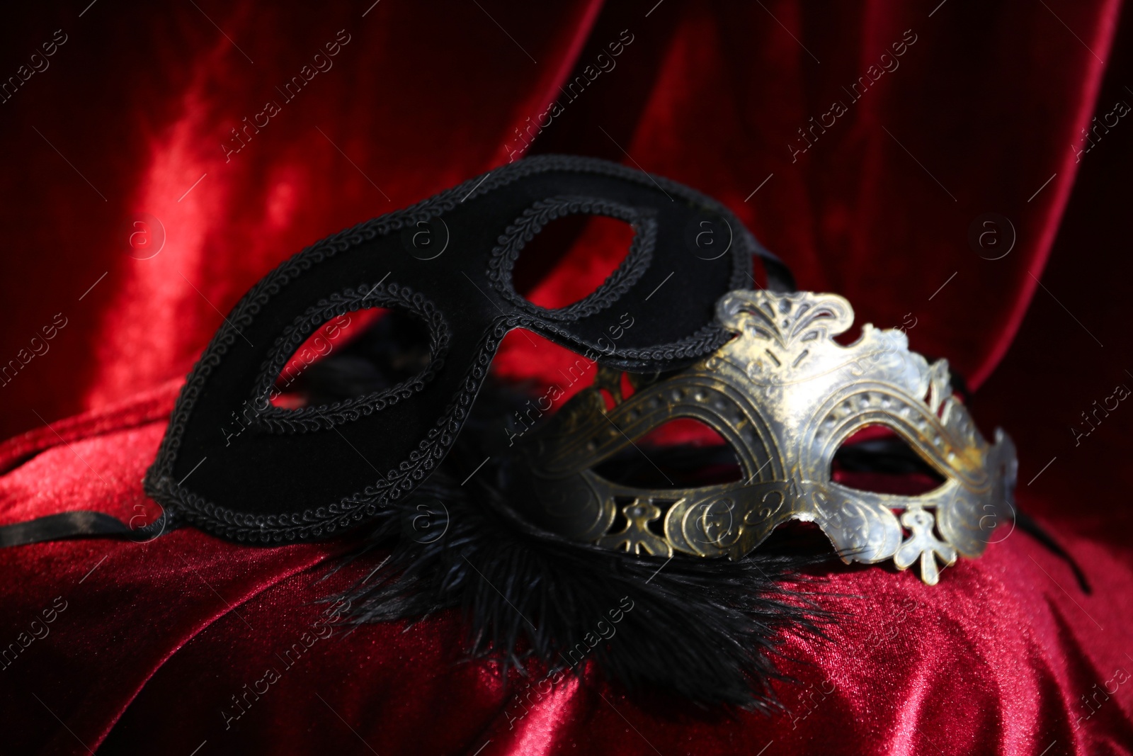 Photo of Beautiful carnival masks on red silk fabric