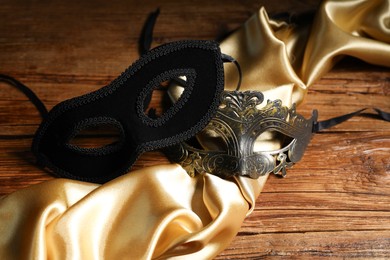 Photo of Beautiful carnival masks and silk fabric on wooden table