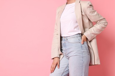 Woman in beige jacket and jeans on pink background, closeup. Space for text