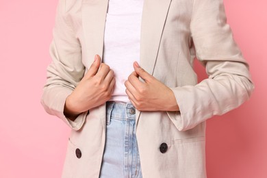 Woman in beige jacket and jeans on pink background, closeup