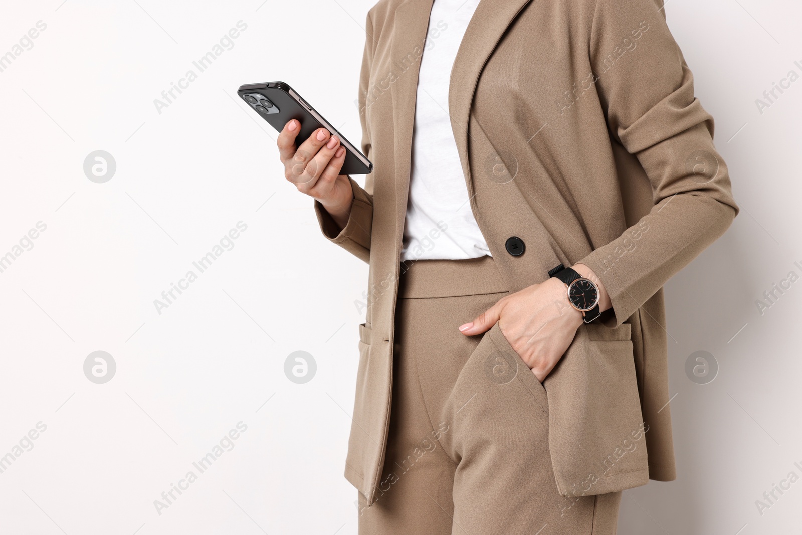 Photo of Woman in beige suit using smartphone on white background, closeup. Space for text