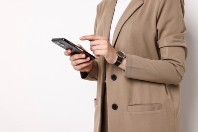 Woman in beige suit using smartphone on white background, closeup. Space for text