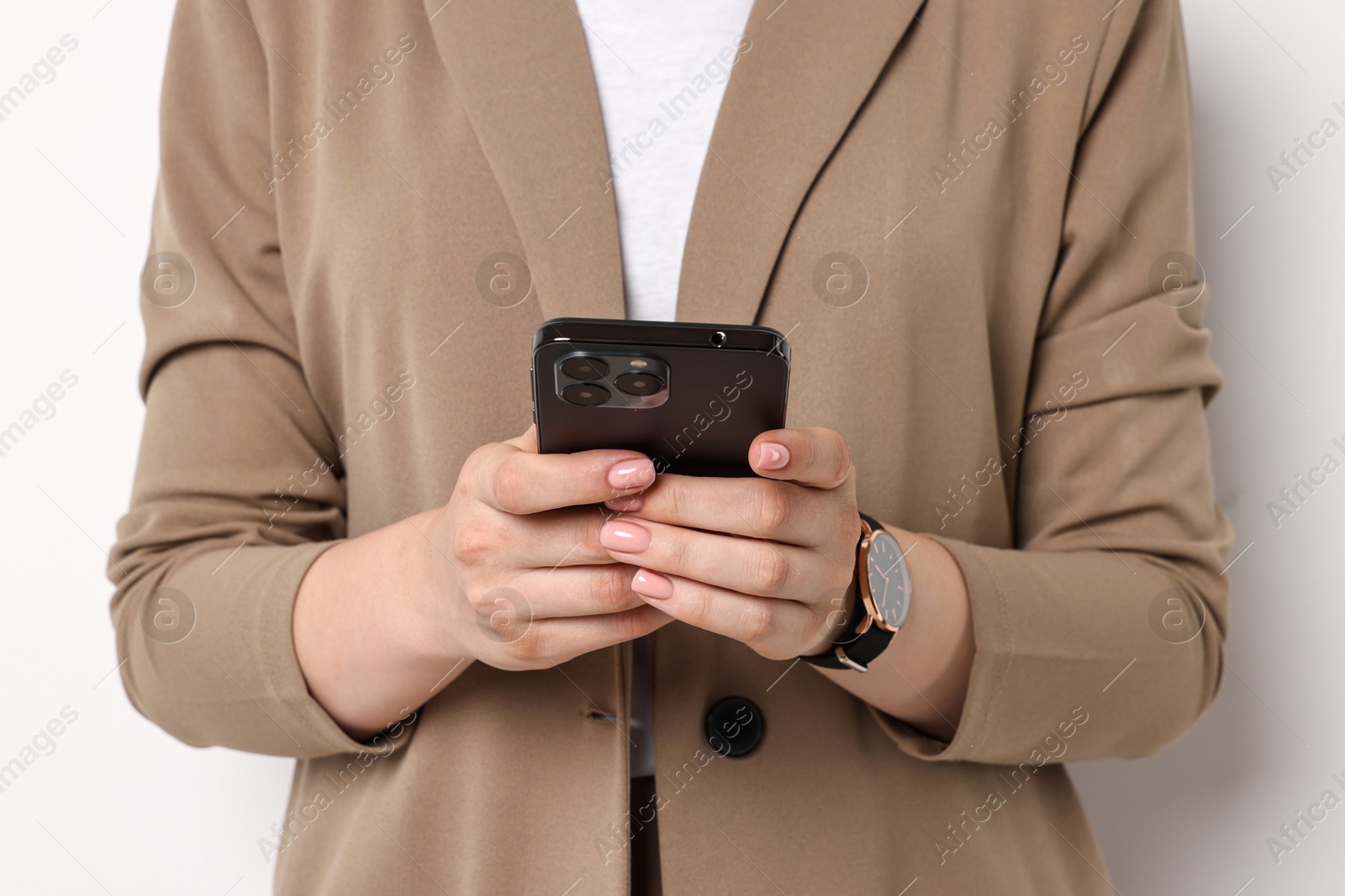 Photo of Woman in beige suit using smartphone on white background, closeup