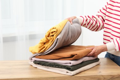 Photo of Woman folding clothes at wooden table indoors, closeup