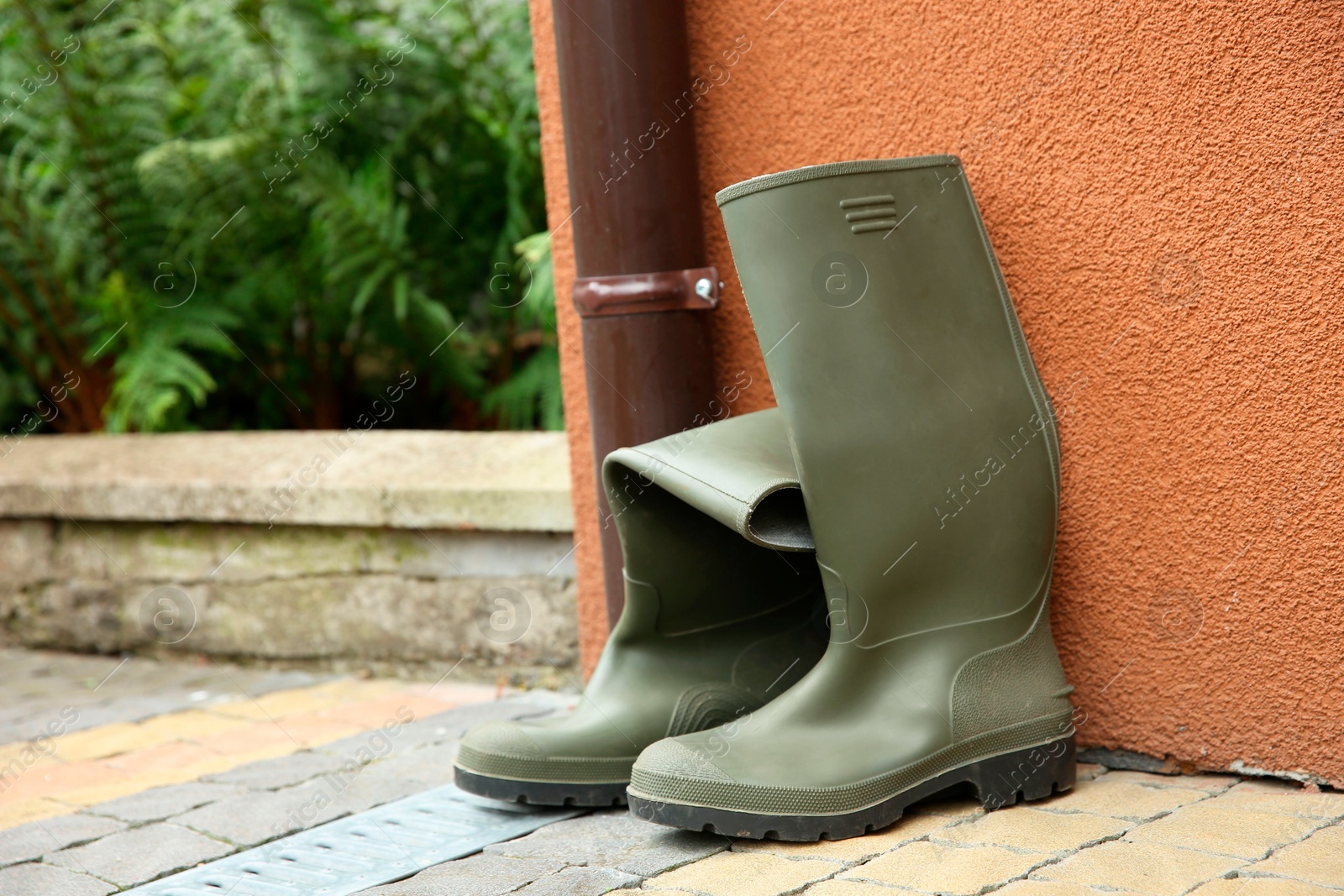 Photo of Grey rubber boots on pavement near wall outdoors