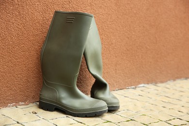 Photo of Grey rubber boots on pavement near wall outdoors