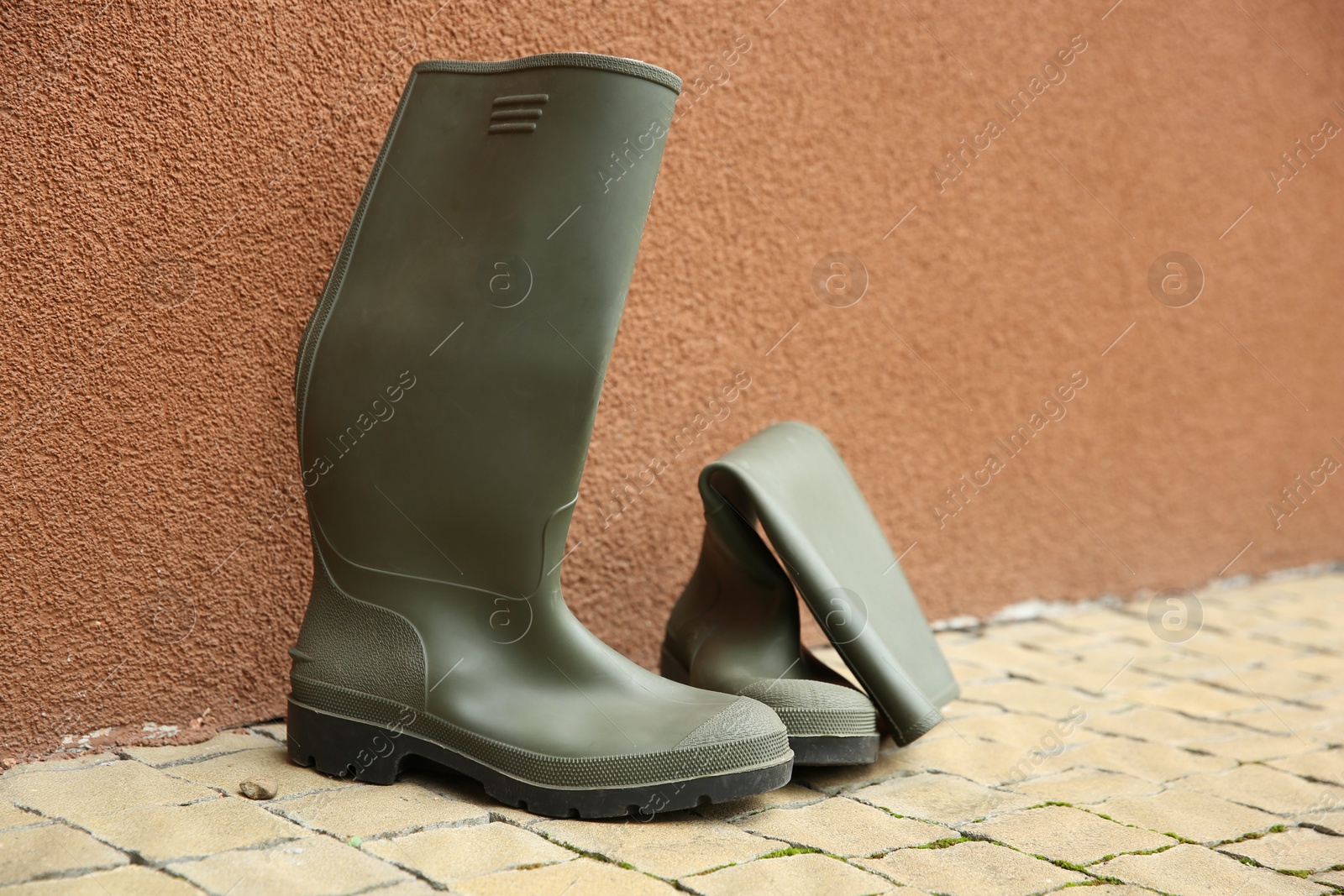 Photo of Grey rubber boots on pavement near wall outdoors