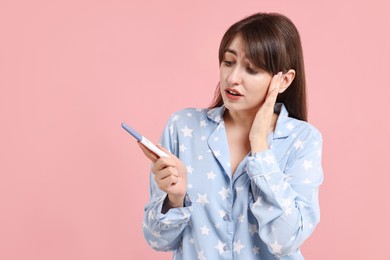 Worried young woman with pregnancy test on pink background, space for text