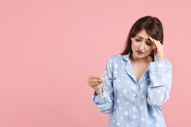 Photo of Worried young woman with pregnancy test on pink background, space for text